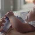Child lying on bed with nebuliser mask on face.